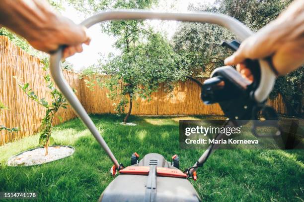 man using a lawn mower in his back yard. - garden machinery stock pictures, royalty-free photos & images