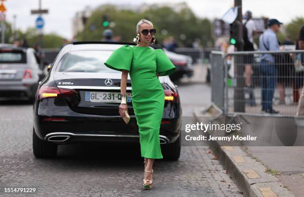 Denisa Palsha seen wearing Dior black squared sunglasses, gold statement earrings and gold statement bracelet, Solace London green midi dress with...