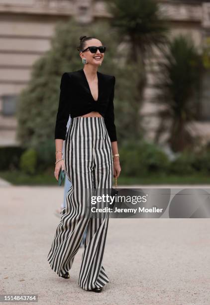 Kristina Romanova seen outside Schiaparelli show wearing black Saint Laurent sunnies, big Schiaparelli earrings, cropped black suede blazer, gold...