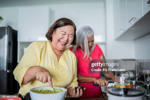 mature women preparing guacamole at a domestic kitchen - reunion familia stock pictures, royalty-free photos & images