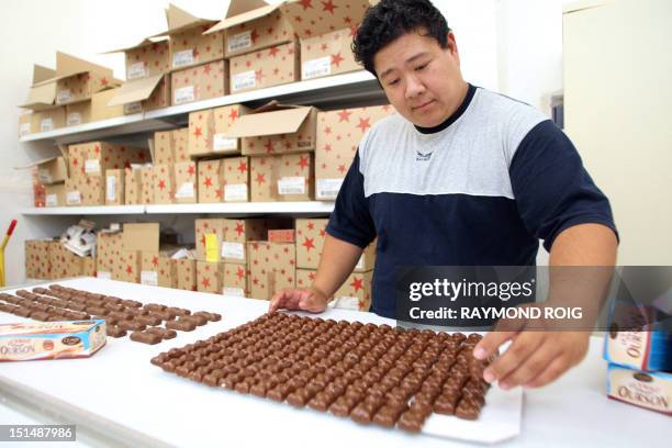 An employee selects coated marshmallow bears on August 23 at the factory of the French group CEMOI, specialized in the manufacturing of confectionery...
