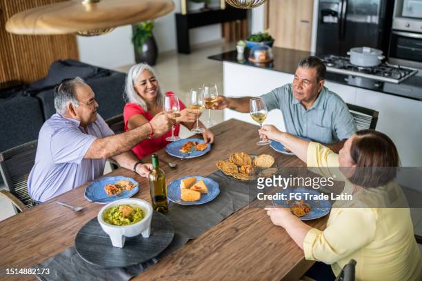 senior friends making a toast while having lunch at home - mexican food and drink stock pictures, royalty-free photos & images