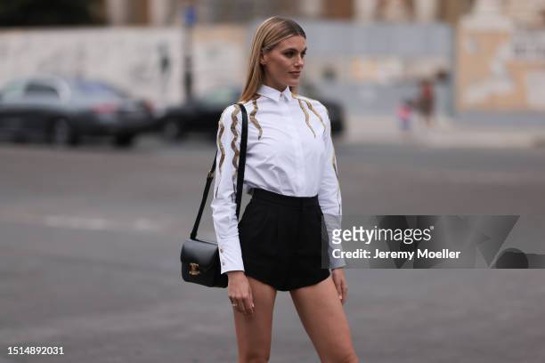 Guest seen outside Schiaparelli show wearing white shirt with gold details, black hot pants, gold and black high heels and black shoulder bag during...
