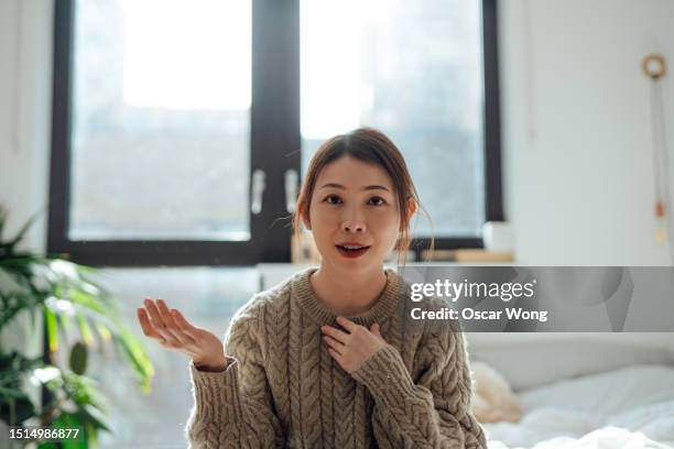 portrait of young asian woman gesturing while having a video call - webcam stock-fotos und bilder