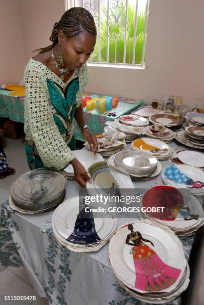 Senegal: une Française met la peinture sous verre à table' by Coumba SYLLA Oumy, assistant to French Veronique Janvier, piled up plates in the...