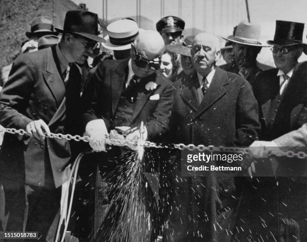 Mayor Angelo Rossi puts a blowtorch to the silver chain, opening the $35 000 Golden Gate Bridge. To his right stands Timothy Rearoon the State...