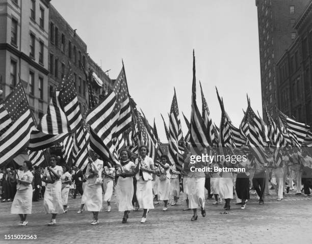 Crowd of women marching with USA flags in a parade sponsored by the American League against War and Fascism, New York City, New York, United States,...