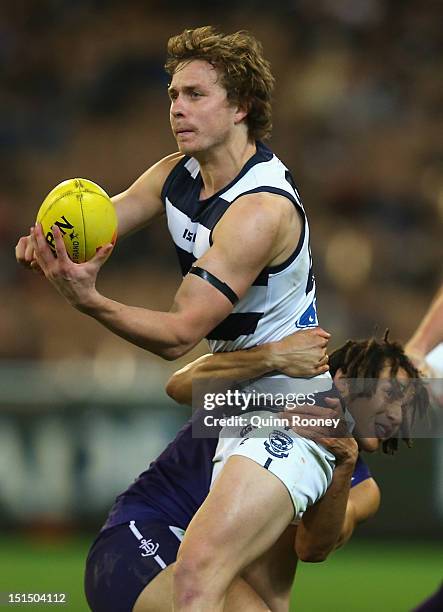 Mitch Duncan of the Cats handballs whilst being tackled by Tendai Mzungu of the Dockers during the Second AFL Elimination Final match between the...