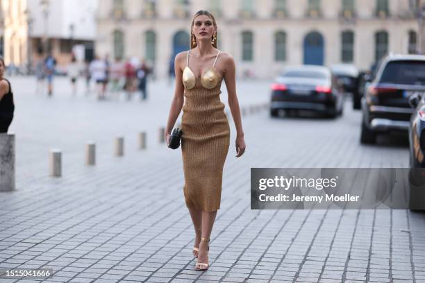 Fashion Week Guest seen wearing a golden Schiaparelli long dress, golden high heels and golden earrings and a black leather clutch outside...