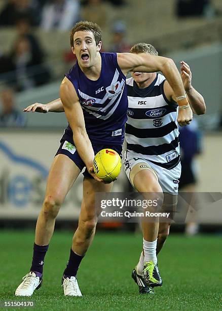 Michael Barlow of the Dockers handballs whilst being tackled by Taylor Hunt of the Cats during the Second AFL Elimination Final match between the...