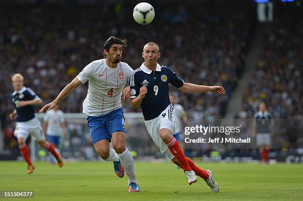 Kenny Miller of Scotland tackles Milan Bisevac of Serbia during the FIFA 2014 World Cup Qualifier at Hampden Park between Scotland and Serbia on...