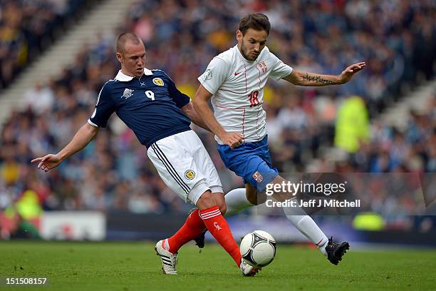 Kenny Miller of Scotland tackles Milos Ninovic of Serbia during the FIFA 2014 World Cup Qualifier at Hampden Park between Scotland and Serbia on...