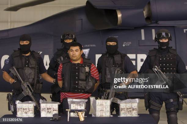 Surrounded by heavily armed police officers, Jaime Gonzalez Duran, a.k.a. "Hummer", founder of a group of hitmen called the "Zetas", is shown to the...