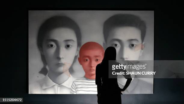Sotheby's employee stands in front of a painting entitled 'big family number 1' by Chinese artist Zhang Xiaogang at Sotheby's auction house, in...