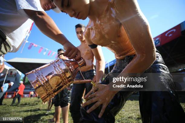 An official helps wrestler boys get their bodies oiled ahead of the last day competition of the 662nd Kirkpinar Oil Wrestling Festival in Edirne,...