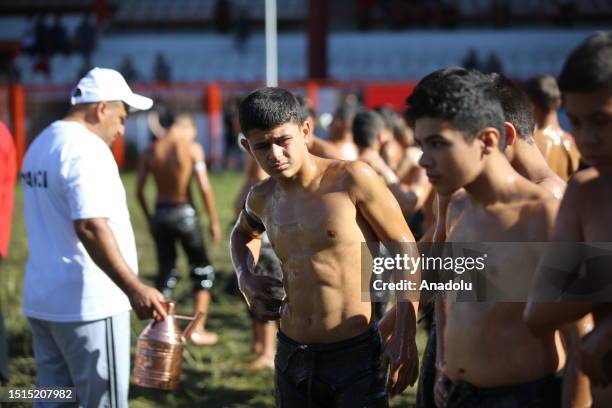 An official helps wrestler boys get their bodies oiled ahead of the last day competition of the 662nd Kirkpinar Oil Wrestling Festival in Edirne,...