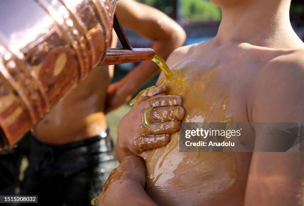 An official helps wrestler boys get their bodies oiled ahead of the last day competition of the 662nd Kirkpinar Oil Wrestling Festival in Edirne,...