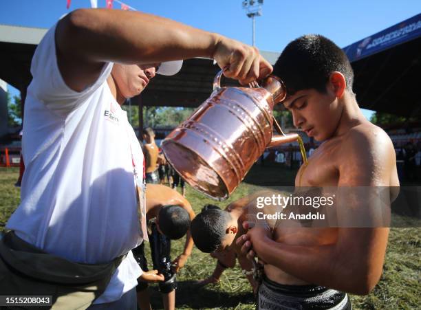 An official helps wrestler boys get their bodies oiled ahead of the last day competition of the 662nd Kirkpinar Oil Wrestling Festival in Edirne,...