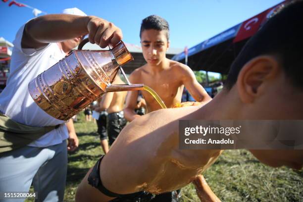 An official helps wrestler boys get their bodies oiled ahead of the last day competition of the 662nd Kirkpinar Oil Wrestling Festival in Edirne,...