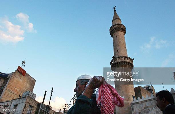 Jordanian man adjusts his kefiah as he walks out from a mosque October 22, 2002 in downtown Amman, Jordan. Approximately 98% of the population are...