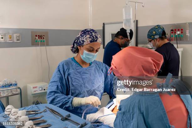 female surgeon doing a cesarean section in the operating room accompanied by the scrub doctor and anesthesiologists - surgical equipment stock pictures, royalty-free photos & images