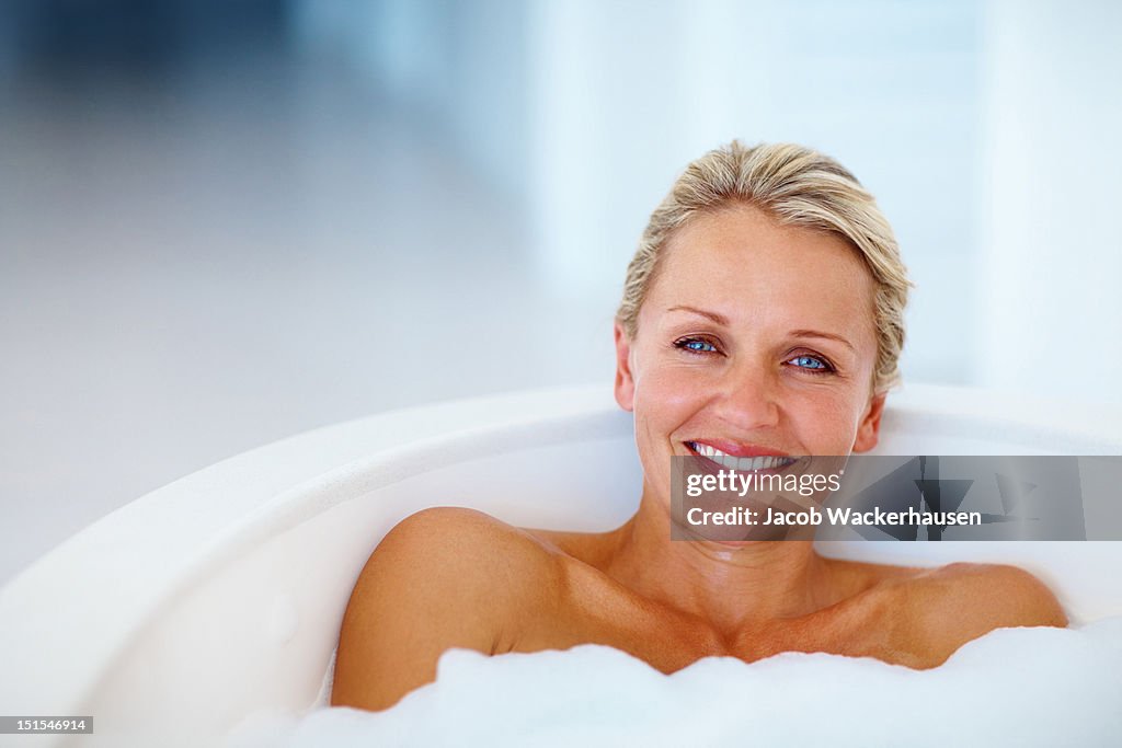 Happy mature woman taking bath