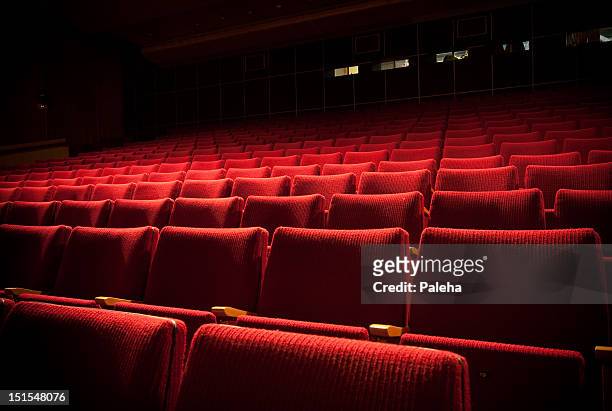 empty theatre with red seats in low light - seat stock pictures, royalty-free photos & images
