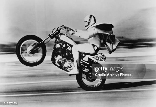 American stunt rider Evel Knievel pulls a wheelie on his Harley Davidson motorcycle, circa 1975.