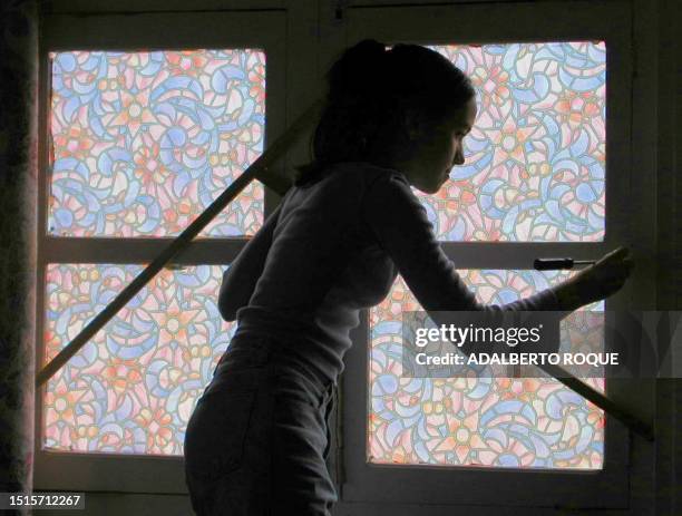 Young woman secures a window 03 November 2001 in Havana in preparation for Hurricane Michelle. Packing strong winds and driving rains, Hurricane...