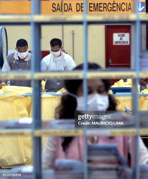 Brazilian postal worker wears a mask and gloves to protect herself from anthrax while sorting mail bound for New York 25 October, 2001 in Sao Paulo....