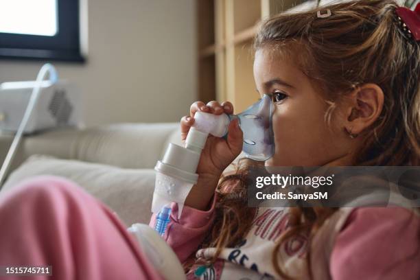 bambina che usa il nebulizzatore durante l'inalazione della terapia - apparecchio per la respirazione foto e immagini stock