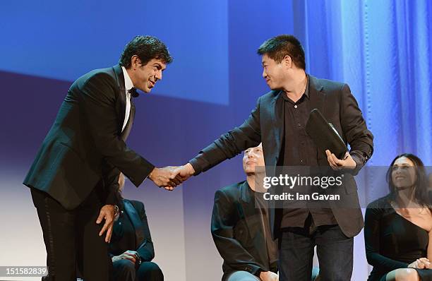 Director Wang Bing shakes hands with Jury President Pierfrancesco Favino as he wins the Orizzonti Award for Best Film on stage during the Award...