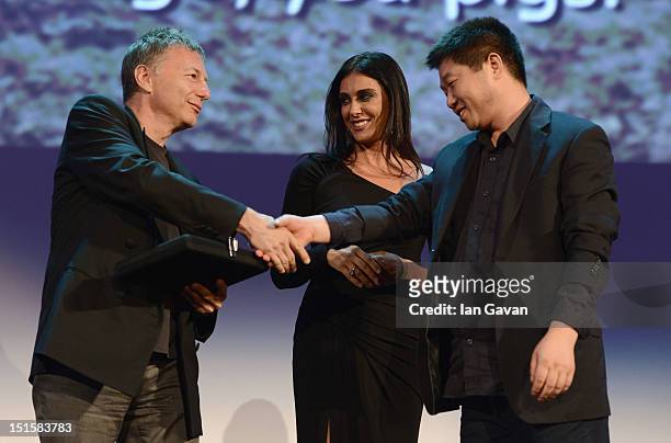 Director Wang Bing as he wins the Orizzonti Award for Best Film on stage with jury members Milcho Manchevski and Nadine Labaki during the Award...