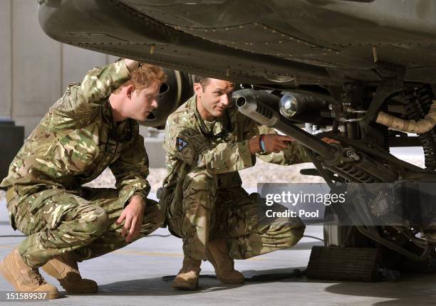 Prince Harry examines the 30mm cannon of an Apache helicopter with a member of his squadron on September 7, 2012 at Camp Bastion, Afghanistan. Prince...