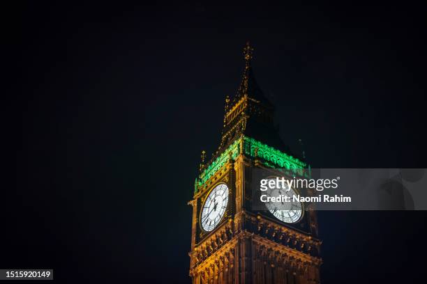 close-up of big ben clock face illuminated at night in london - big ben night stock pictures, royalty-free photos & images
