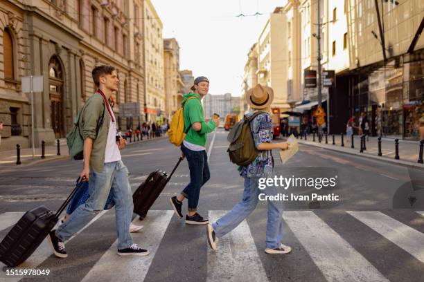 groupe de touristes heureux marchant sur le passage pour piétons de la rue de la ville. - escapade urbaine photos et images de collection