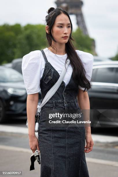 Model wears a white t-shirt with puff sleeves, black denim dress and white crossbody bag, outside Chanel, during the Haute Couture Fall/Winter...