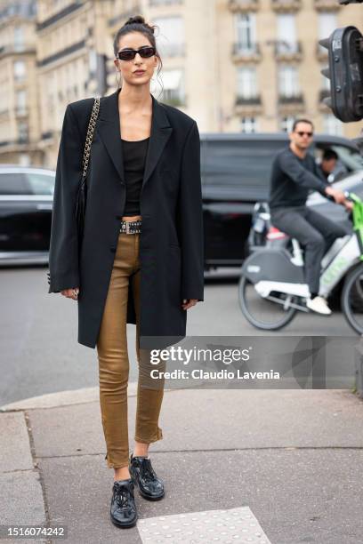 Nora Attal wears a black tank top, black long blazer, tan skinny jeans and black shoes, outside Chanel, during the Haute Couture Fall/Winter...