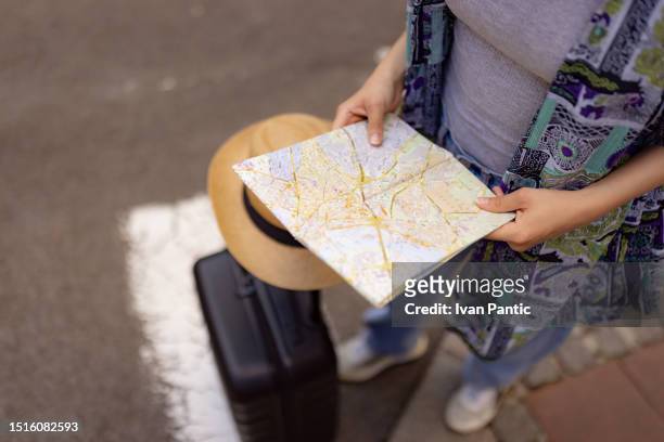 close up of unrecognizable tourist going through city map on the street. - tourist map stock pictures, royalty-free photos & images