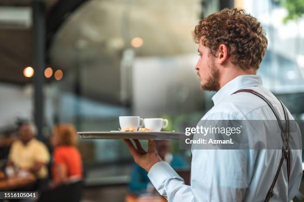 accomplished caucasian waiter serving artisan coffee in a modern cafe - travessa imagens e fotografias de stock