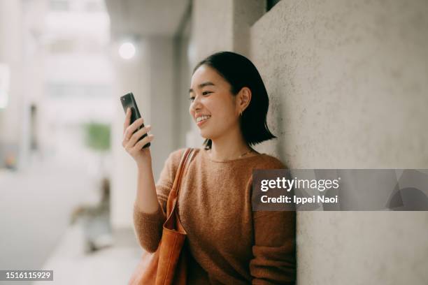 woman on video call using mobile phone on street - teléfono inteligente fotografías e imágenes de stock