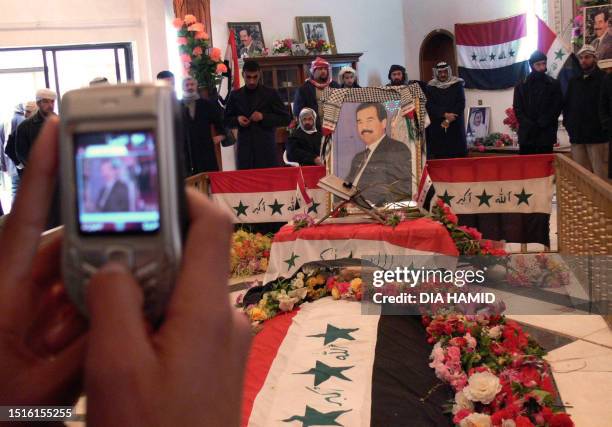 Man uses a mobile phone to take a picture at the grave of hanged dictator Saddam Hussein in his home village of Awja, 05 January 2007. Egyptian...