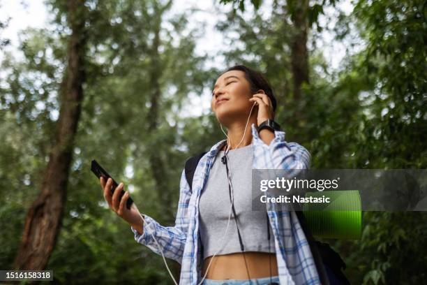 smiling hiking woman with favorite tune - forrest-music stock pictures, royalty-free photos & images