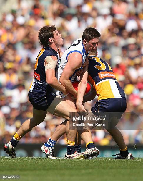 Ryan Bastinac of the Kangaroos gets tackled by Luke Shuey and Adam Selwood of the Eagles during the First AFL Elimination Final match between the...