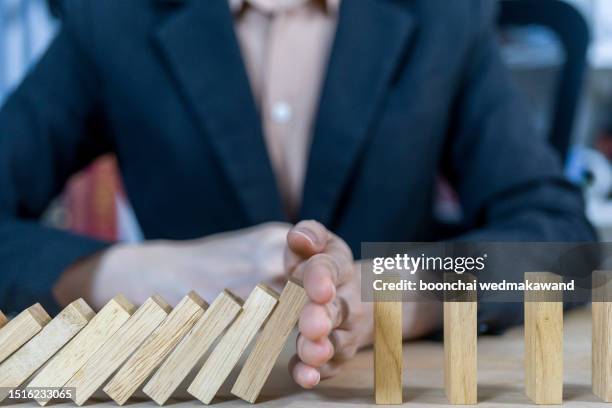 businessman stops the domino effect. - risikomanagement stock-fotos und bilder