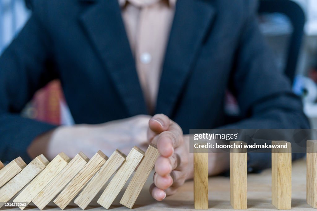 Businessman stops the domino effect.