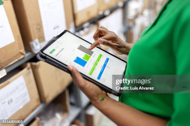close-up of warehouse manager using inventory management system on digital tablet - green hands plant stock-fotos und bilder