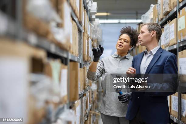 businessman and woman worker taking inventory in distribution warehouse - cargo pants stock-fotos und bilder