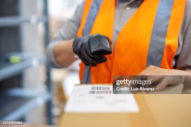 close-up of a woman warehouse worker scanning package with bar code scanner - logistique photos et images de collection