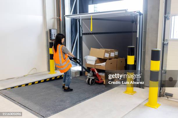 woman worker loading the parcels in a delivert truck using pallet jack in warehouse - muelle de carga fotografías e imágenes de stock